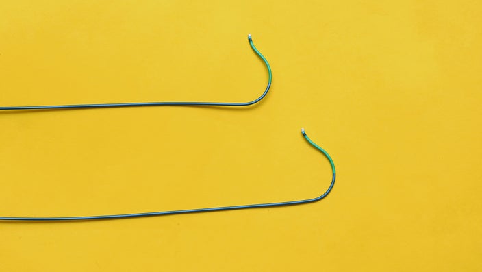 Two guiding wires for stents and balloons to treat blockages during an angioplasty on a yellow background.