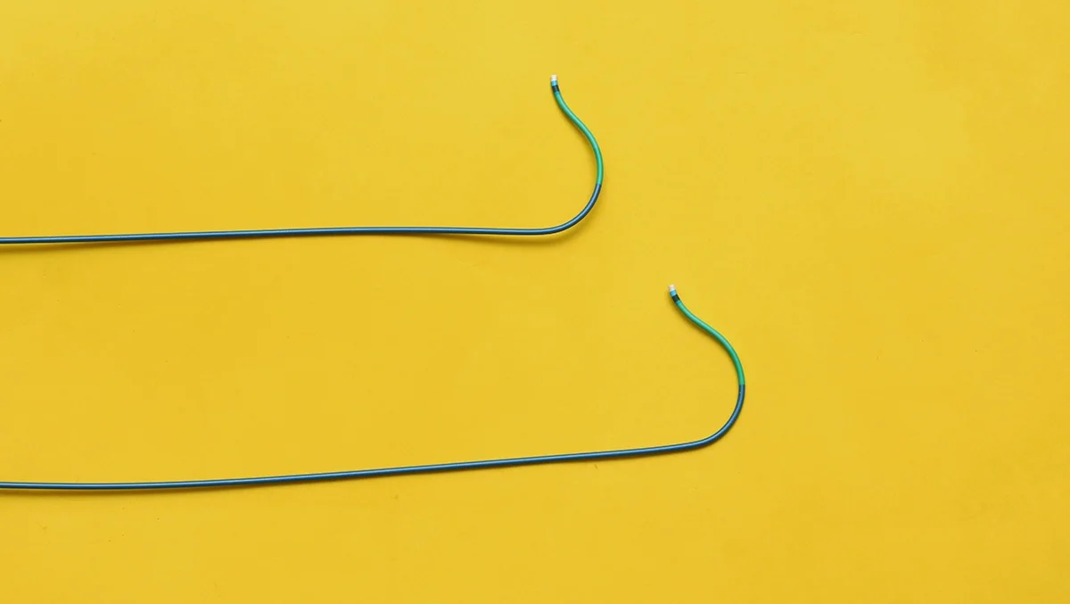 Two guiding wires for stents and balloons to treat blockages during an angioplasty on a yellow background.