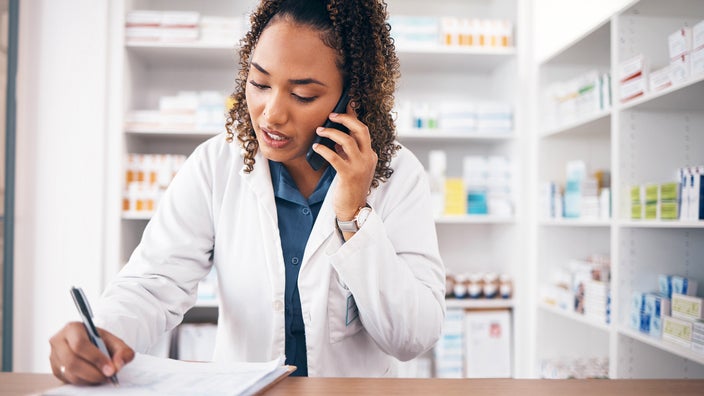 Pharmacist on the phone while taking notes.