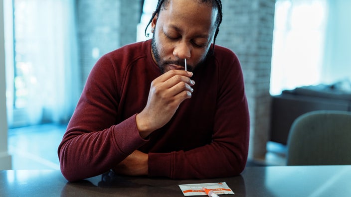 A man uses a nasal swab for an at-home COVID-19 test.