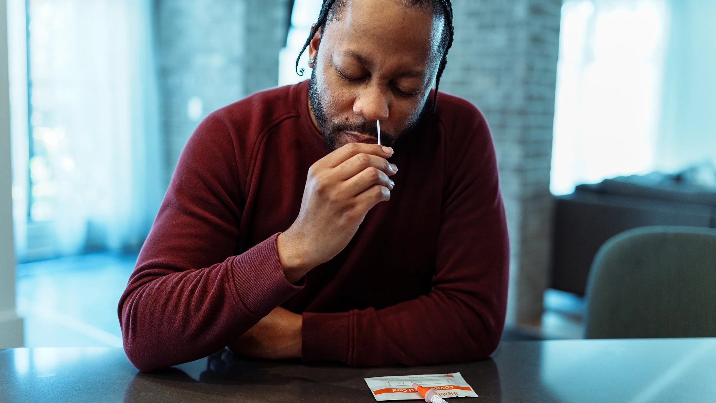 A man uses a nasal swab for an at-home COVID-19 test.