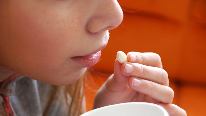 A girl is taking a pill in a close-up. 
