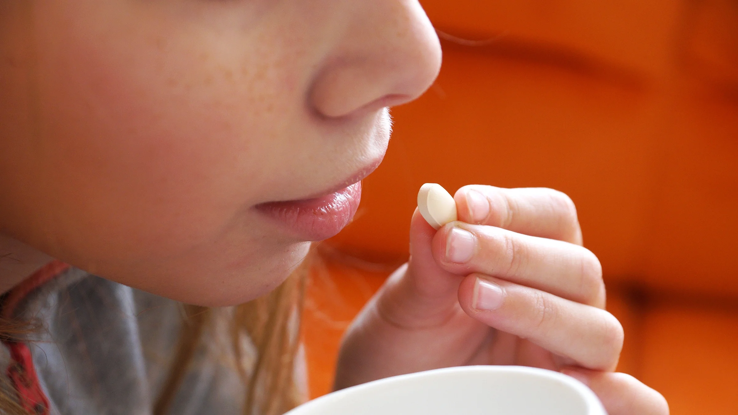 A girl is taking a pill in a close-up.