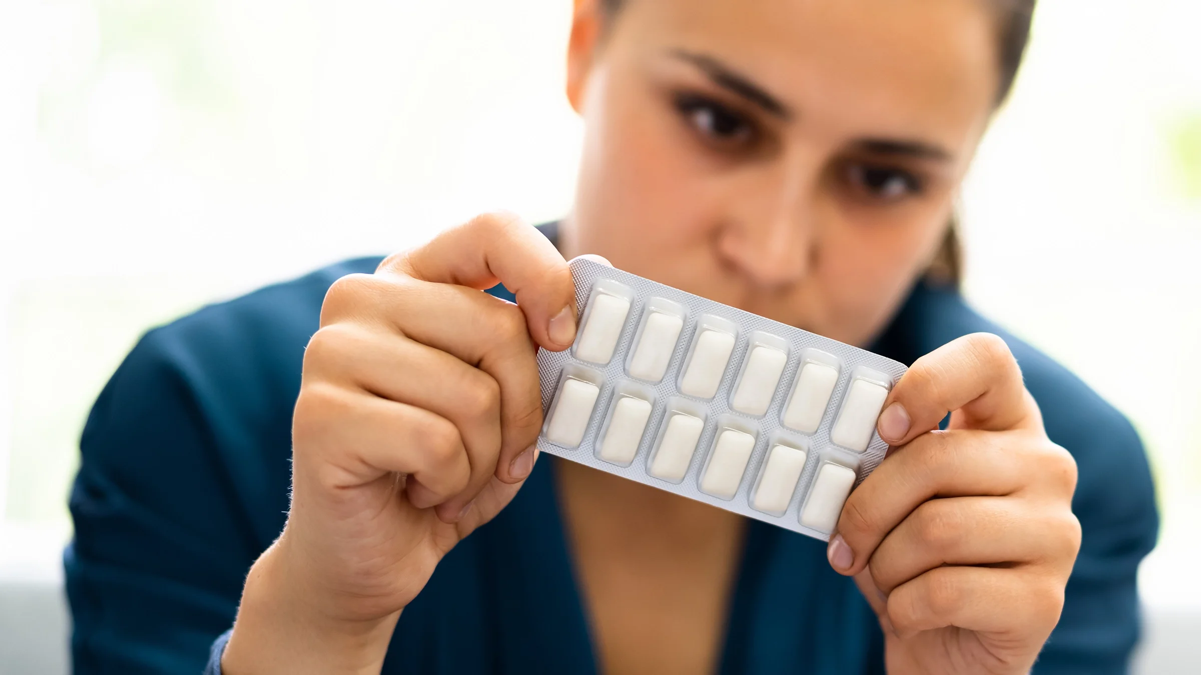 A woman holds a pack of nicotine gum.