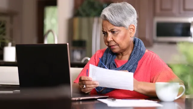 Medicare: woman reviewing paperwork at home 1319260942