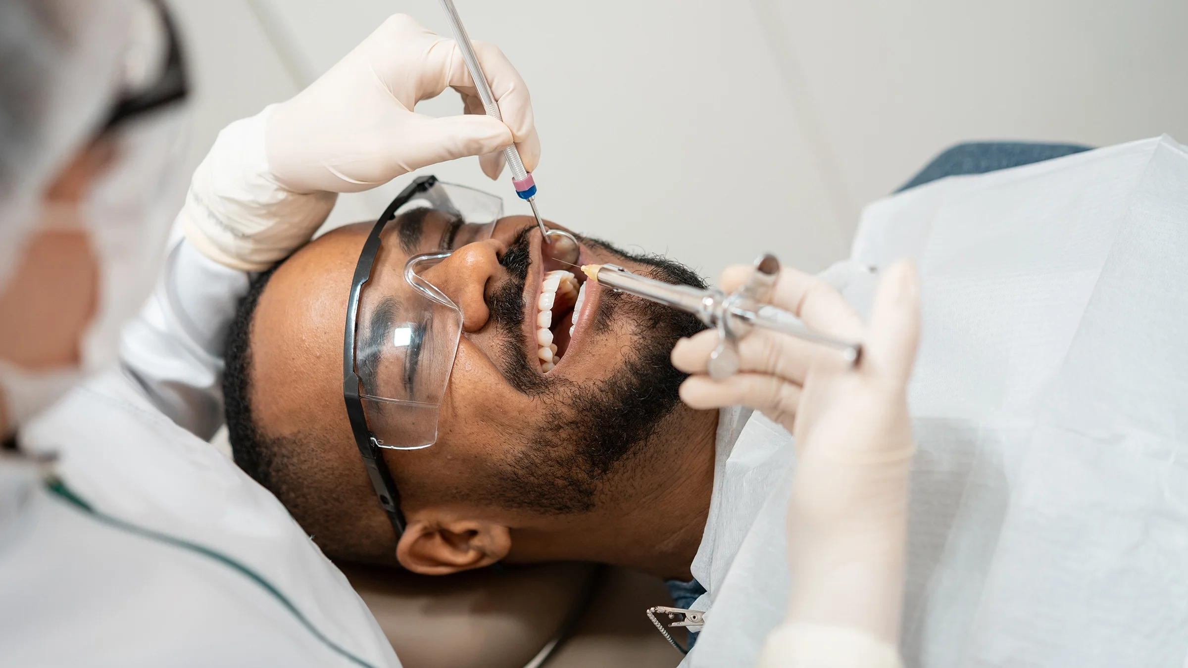 Man smiling in dentist chair as the dentist examines his teeth.