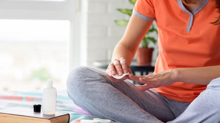 A woman uses nail polish remover.