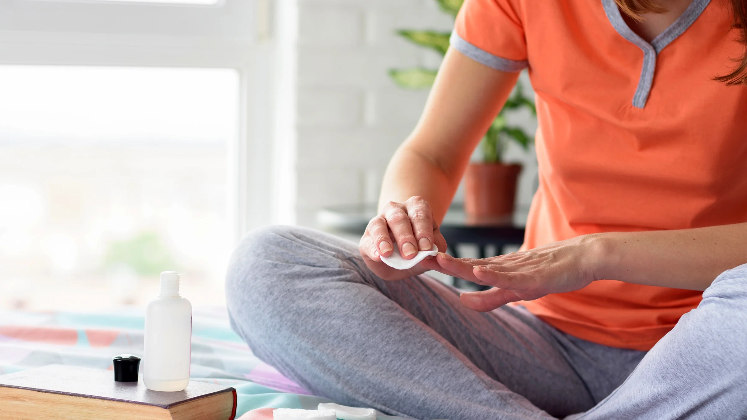 A woman uses nail polish remover.