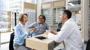 Medicare: senior woman tries on eyeglasses 1492424372