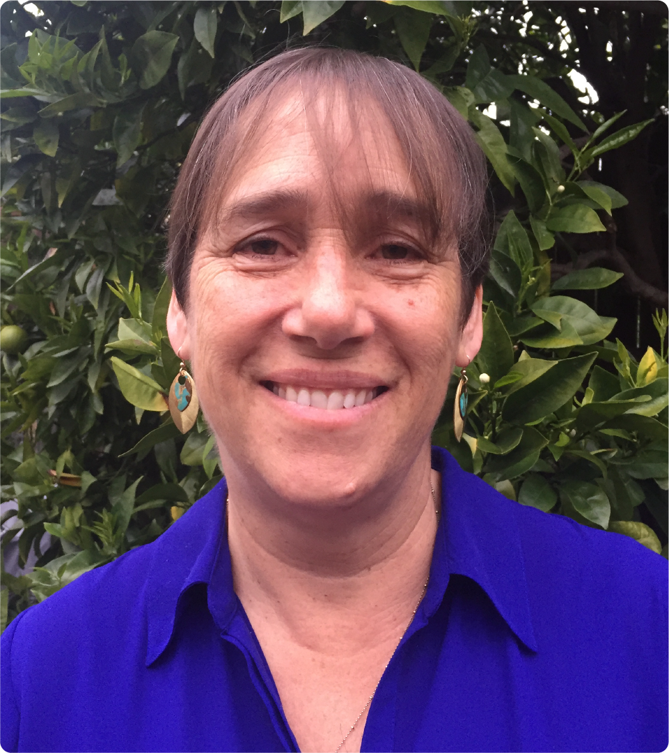 Rebecca Denison is pictured wearing a blue blouse. She is standing in front of a tree.