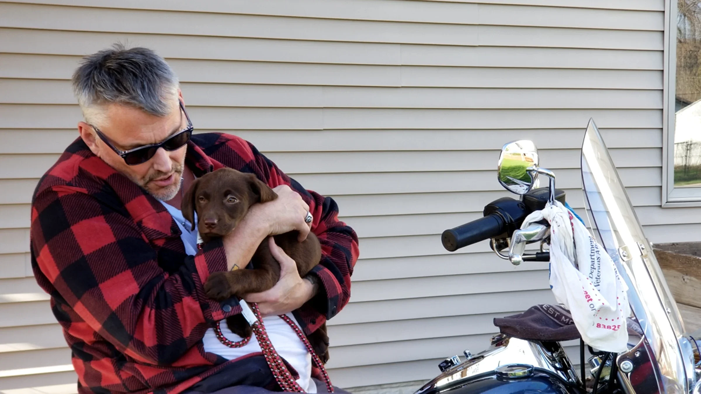 Jim O’Brien is pictured in 2018 sitting on his motorcycle, talking to his dog.
Jim O’Brien, pictured here in 2018 with his dog, has ALS. He turned to AI to save his voice. 