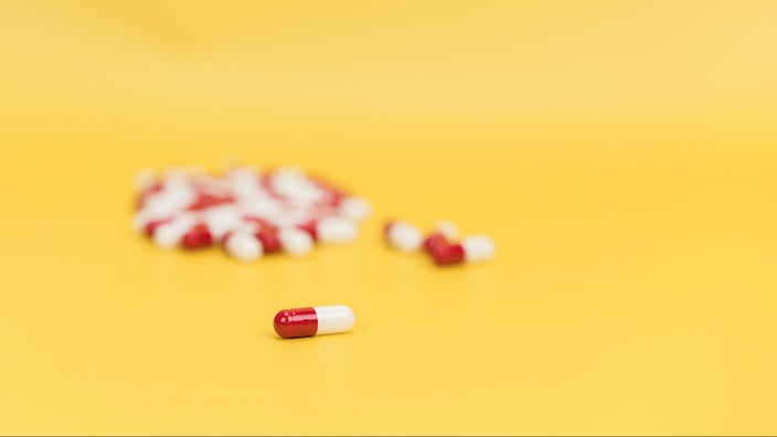 Pile of red and white coated pills on a bright yellow background.	Suphansa Subruayying/iStock via Getty Images