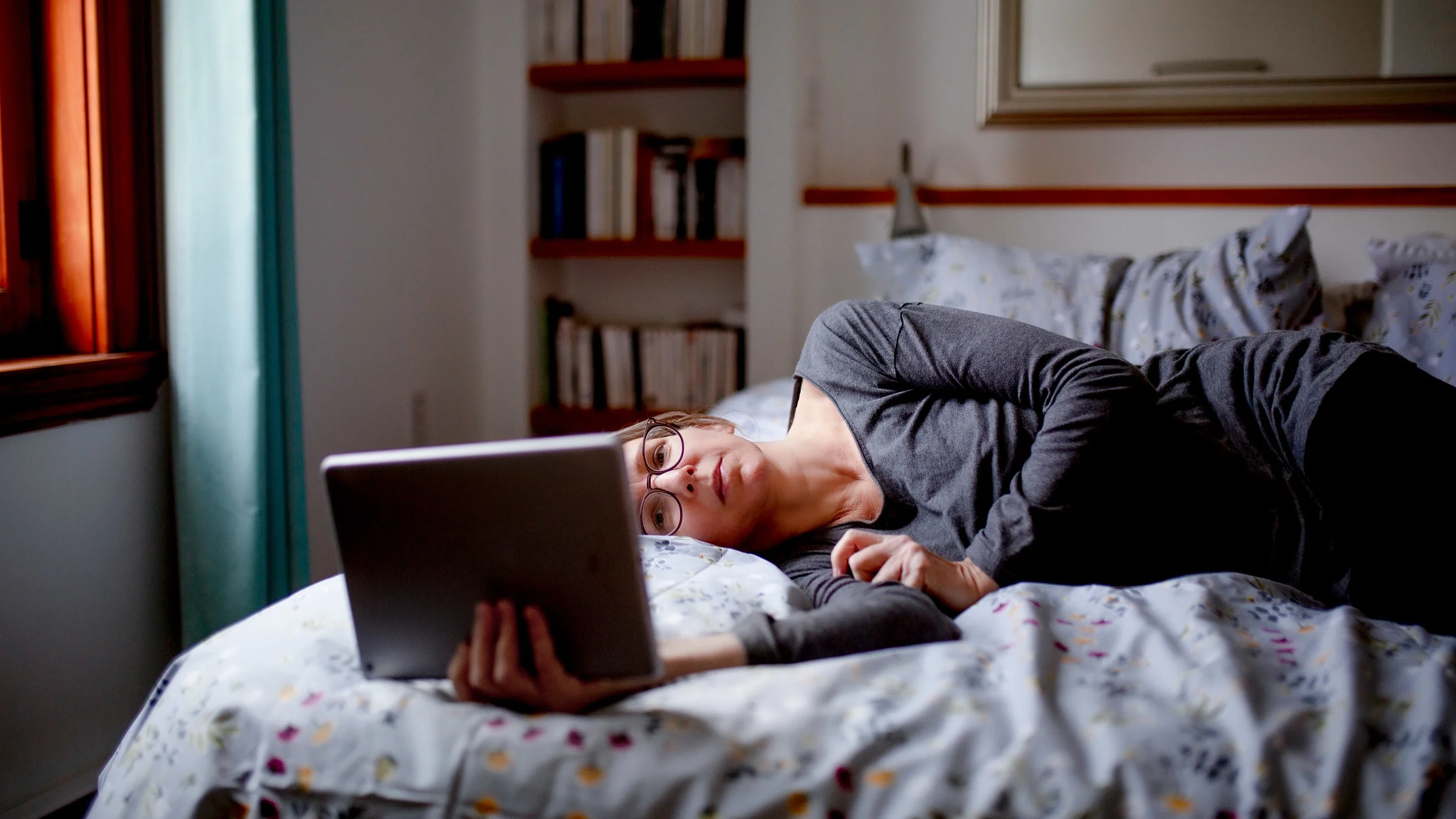 A tired person using tablet in bed.