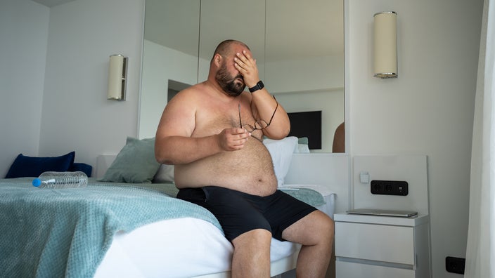 Man sitting on bed shirtless