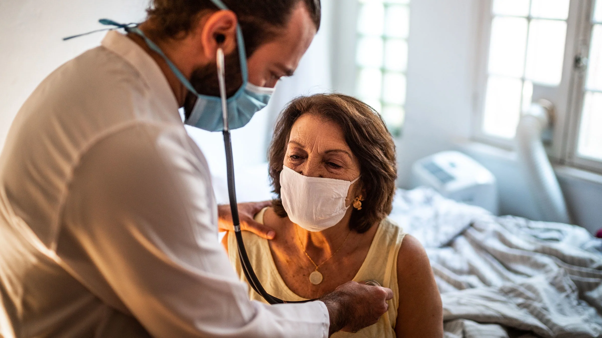 Doctor listens to older patient’s heartbeat.
