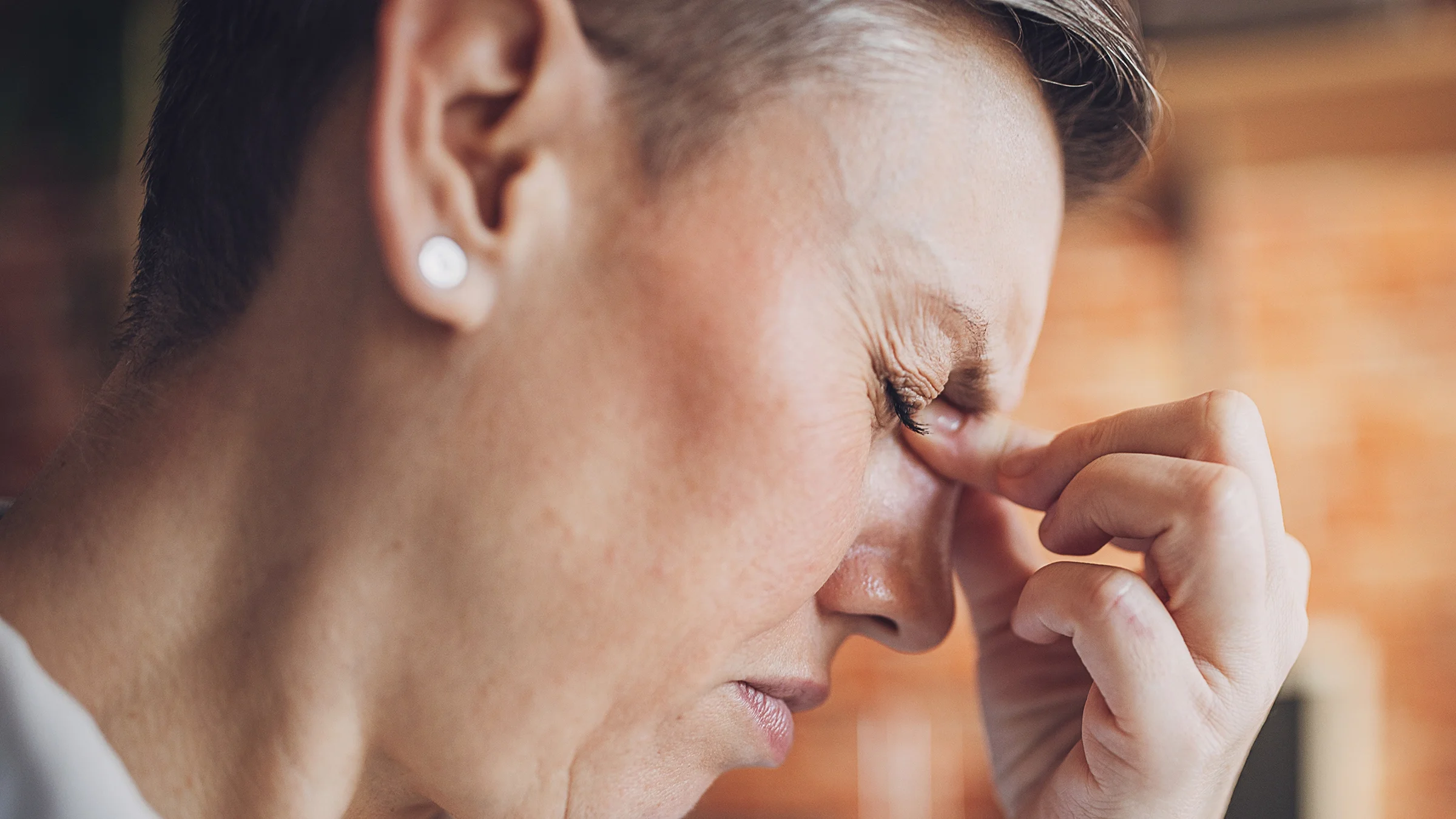 A woman closes her eyes as she experiences discomfort.