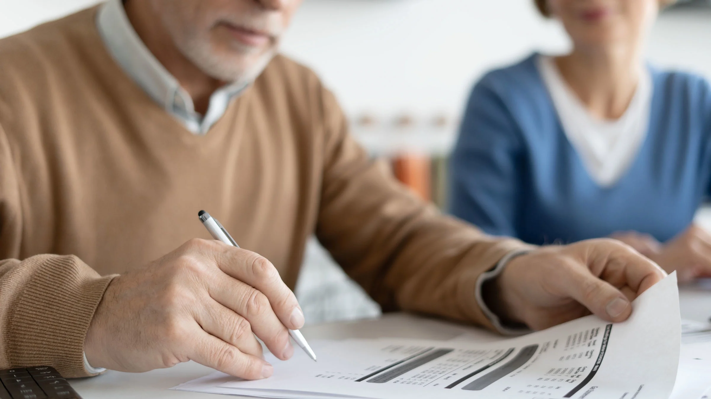 Senior couple signs financial bill.