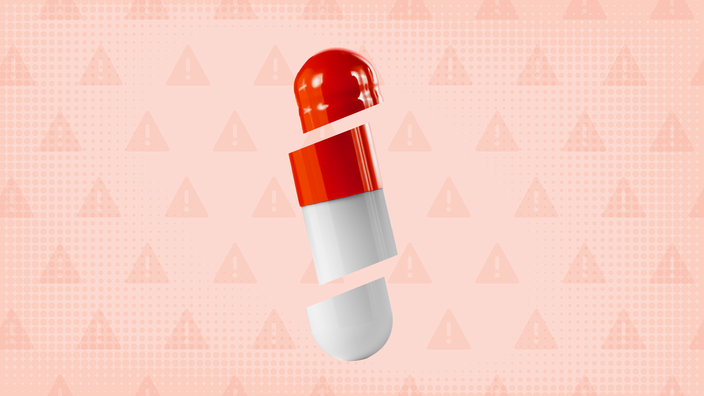 Light red background with texture and warning sign pattern. In the center is a white and red capsule pill cut into thirds.