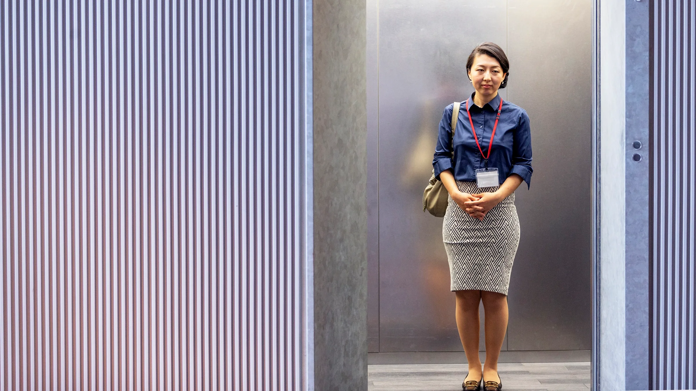 A woman is looking stoic in an elevator at work.
