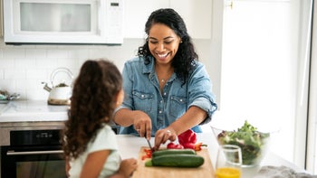 Health: Diet and nutrition: mother daughter cutting vegetables 1285898318