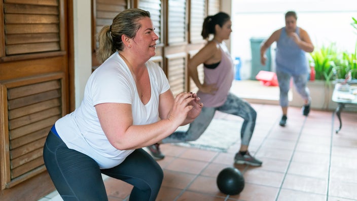 Women in a group fitness class doing lunges and squats.
