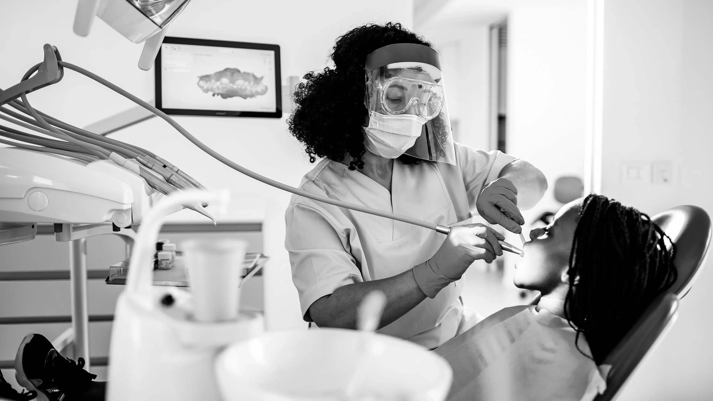 Black and white photo of a person at their teeth cleaning appointment in the dental chair.