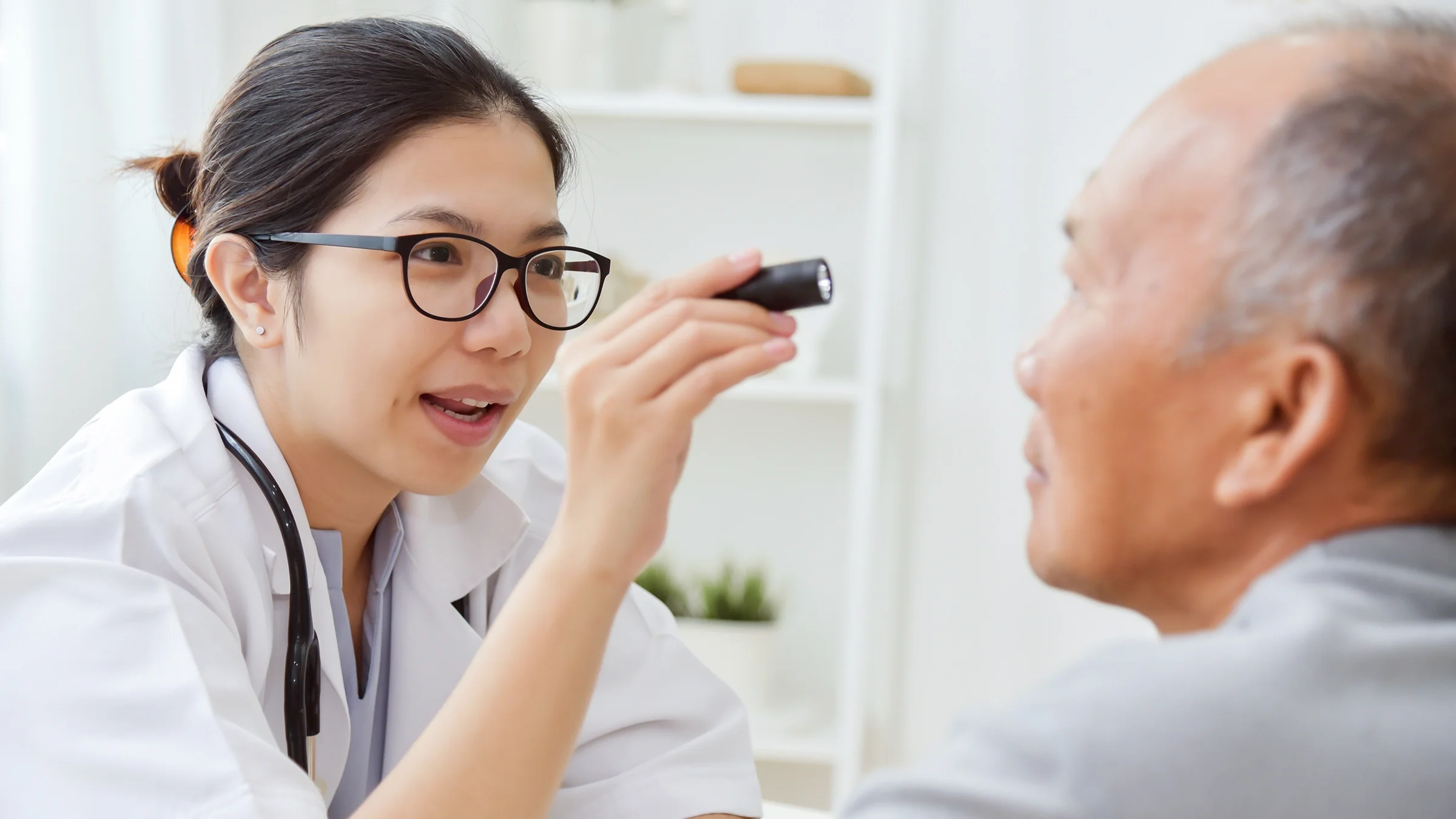Doctor checking patient's eyes with light.