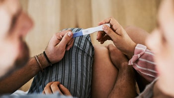 partners reading pregnancy test together-1016585804