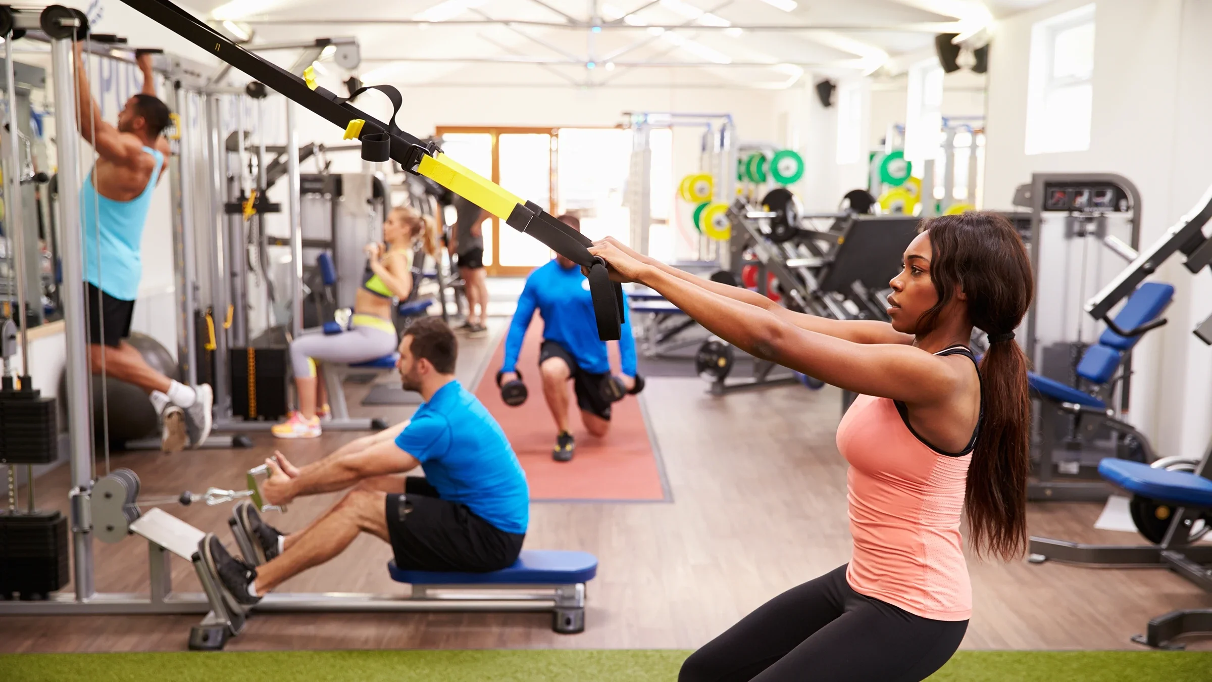 A woman is at the gym doing a TRX exercise.