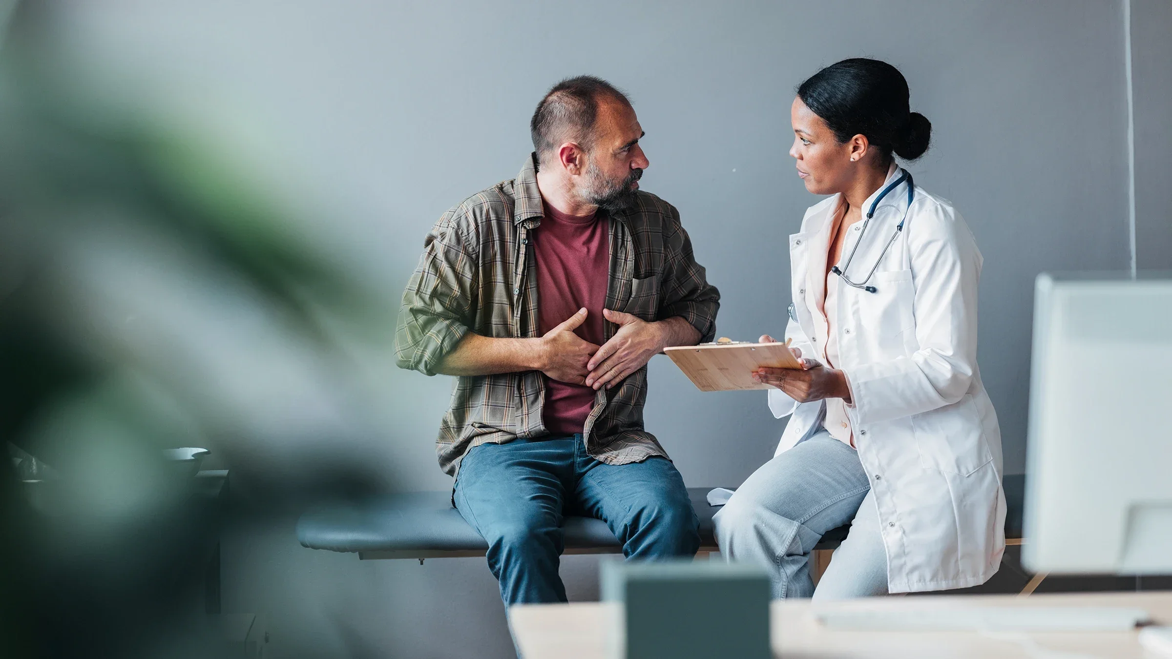 A man gestures toward his abdomen during a medical appointment.
FreshSplash/E+ via Getty Images 