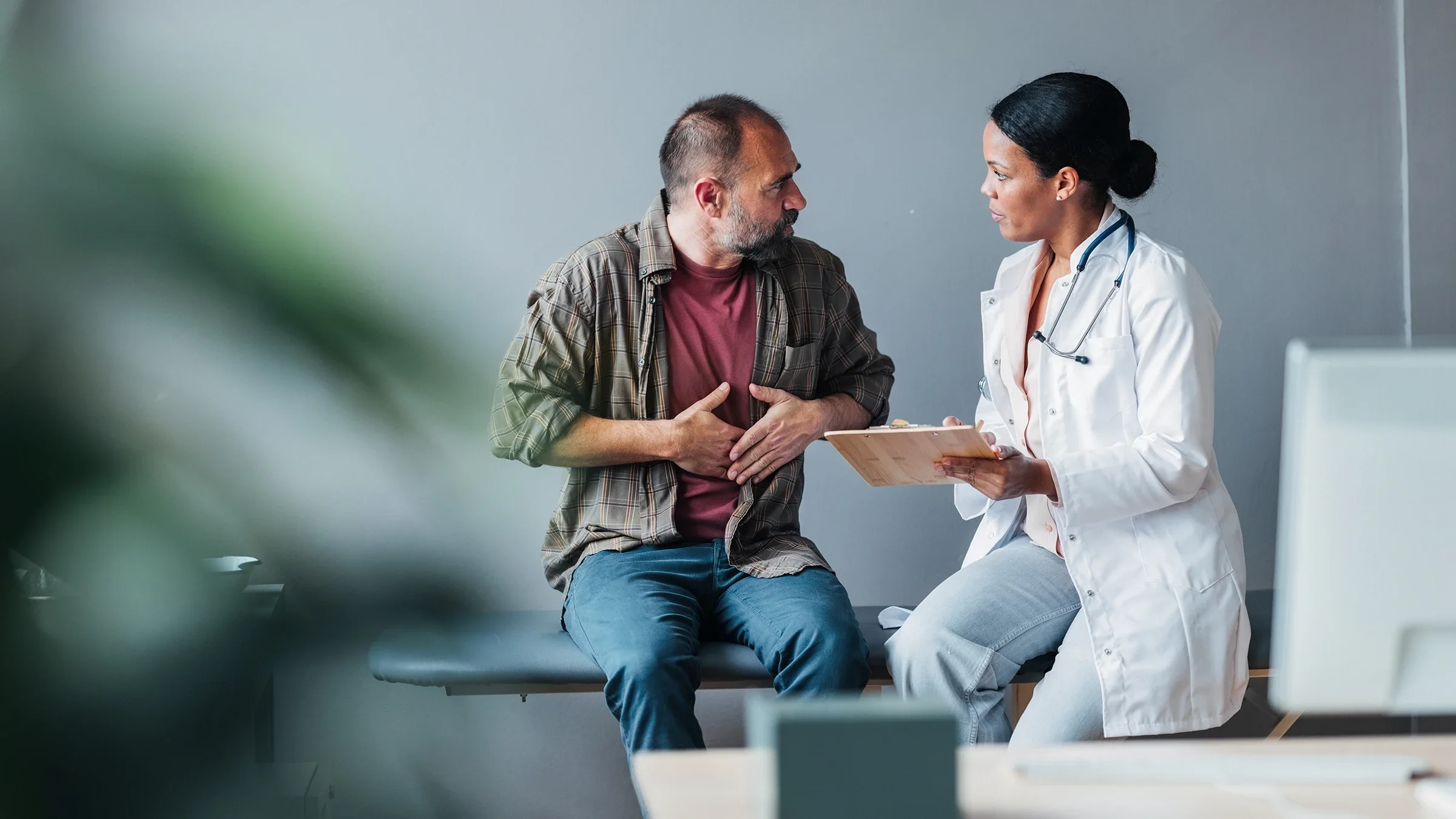 A man gestures toward his abdomen during a medical appointment.