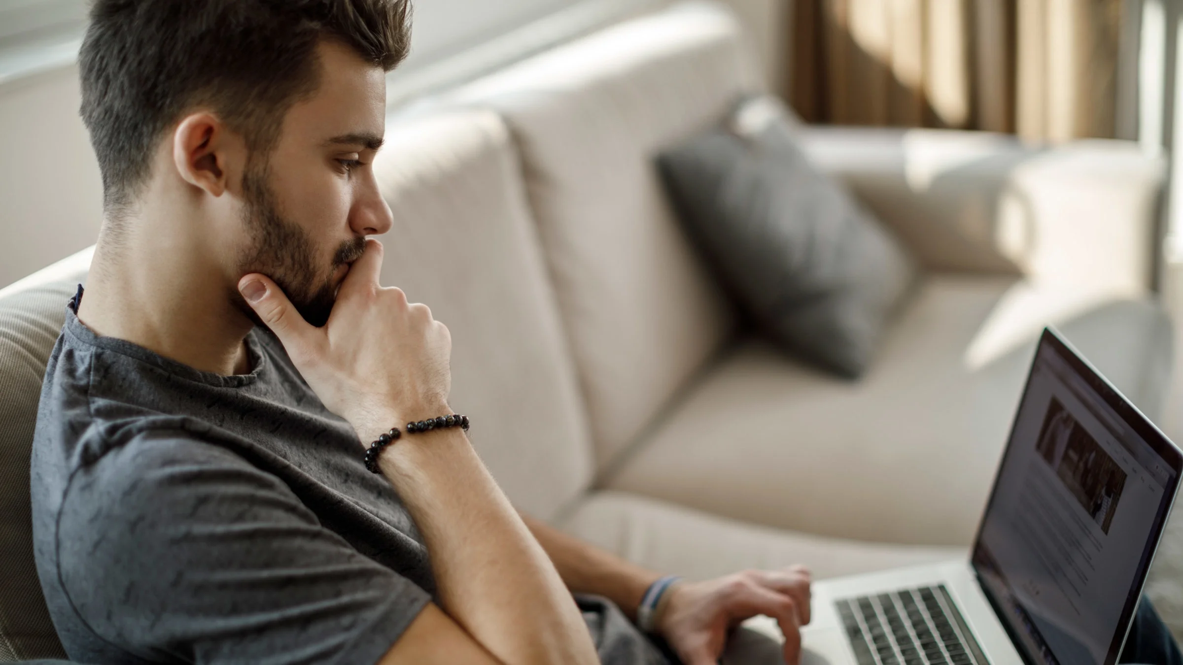 A person sitting on their couch reading an article on their laptop.