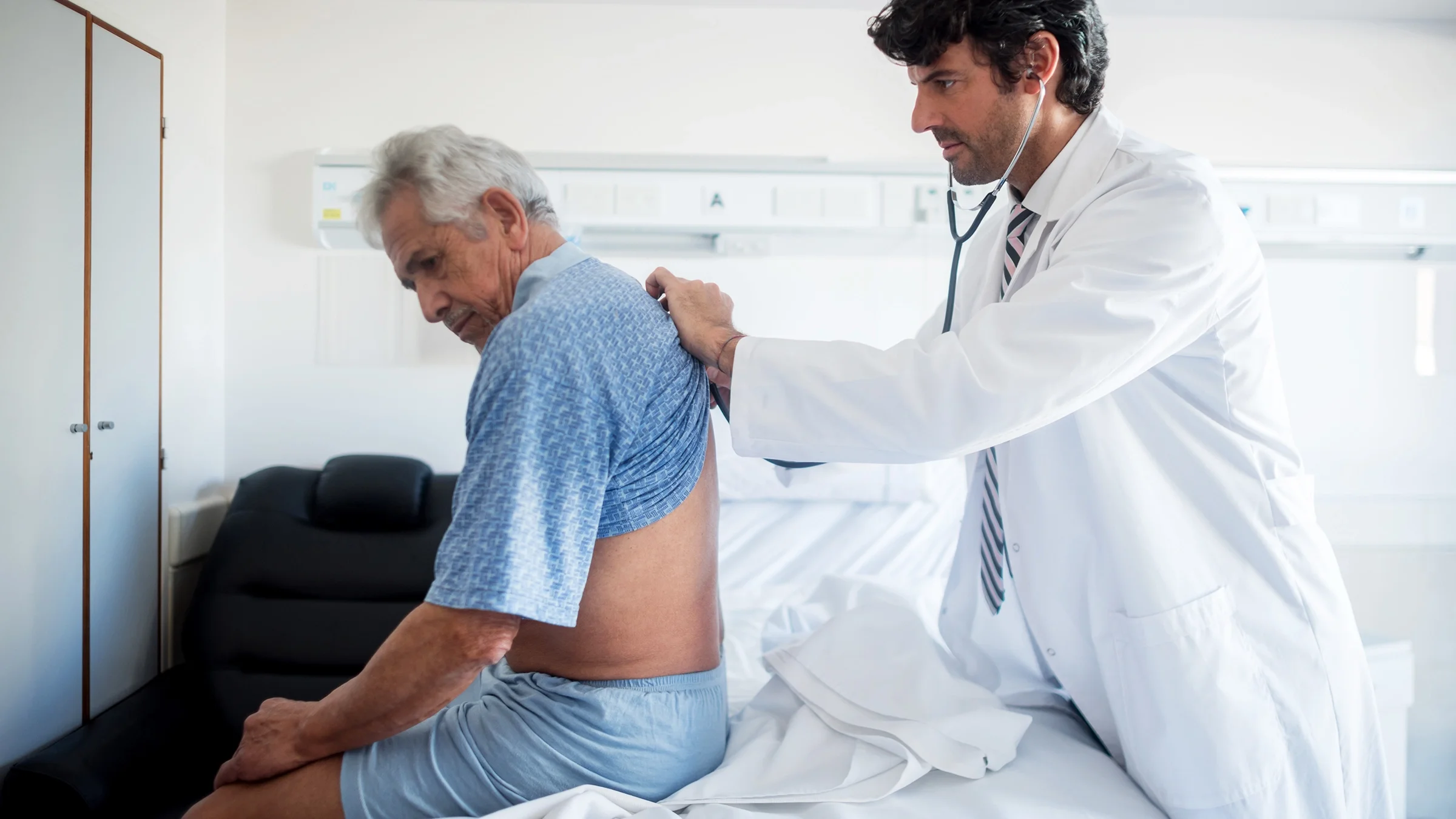 A healthcare professional examines a man’s back. Low back pain is one of the early signs of kidney cancer.