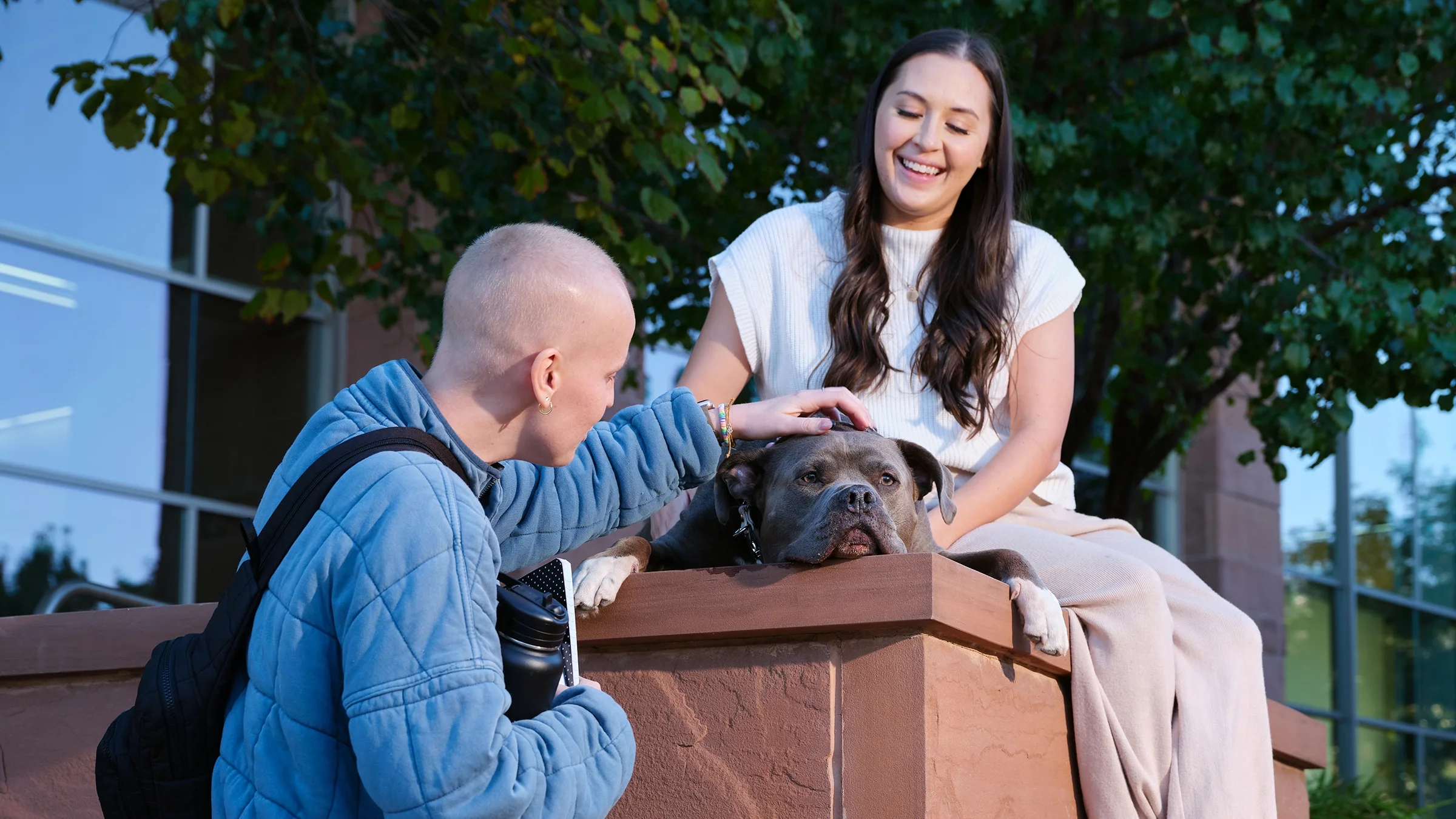 Alisha Benson is pictured visiting a college campus, where a student is petting her pit bull therapy dog, Duke.