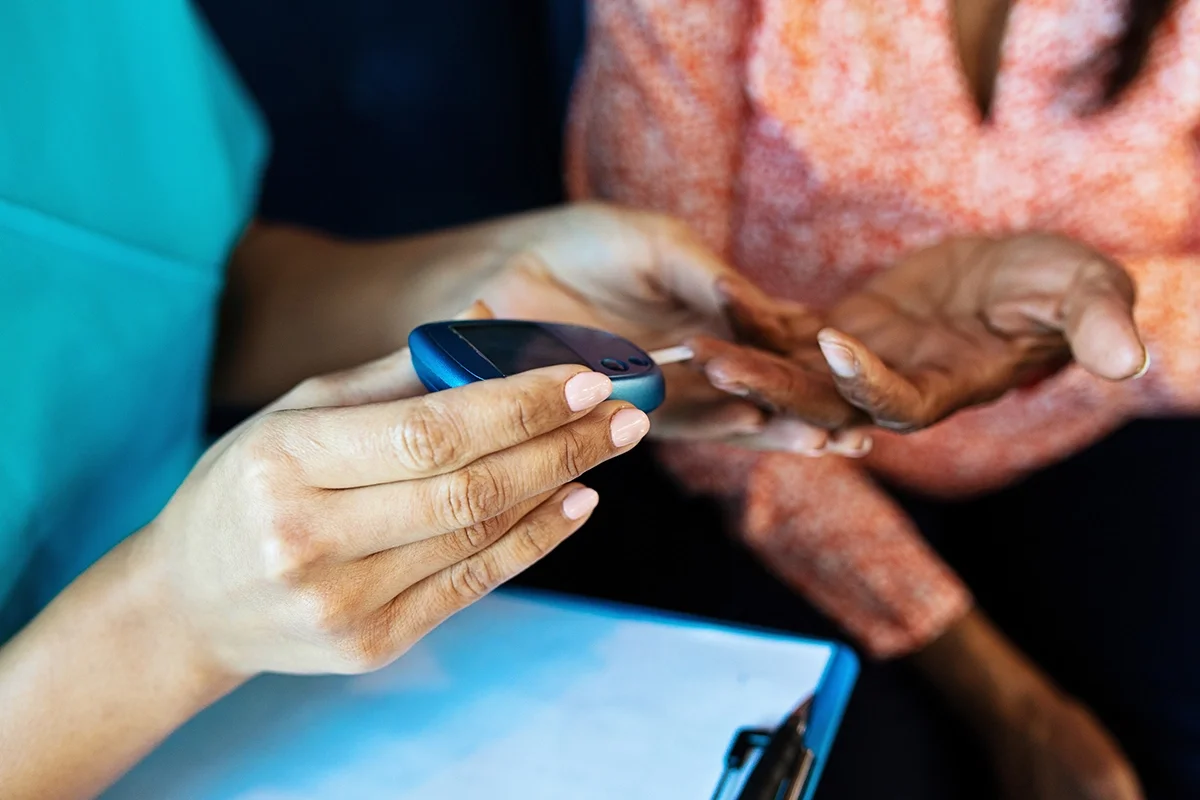 Close-up of a nurse taking a patients blood glucose level with a meter.
