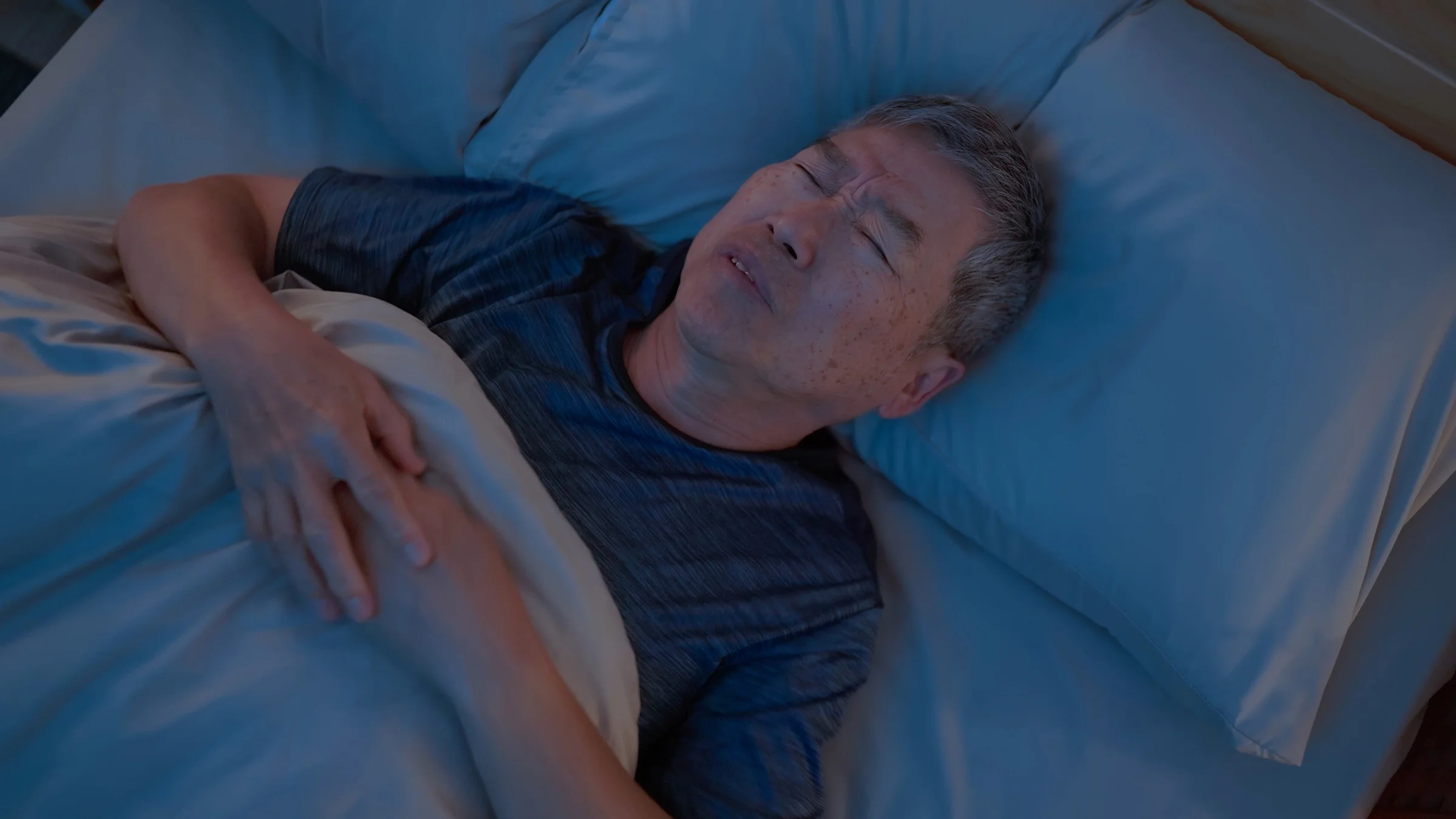 Man lying in bed sleepless at night.