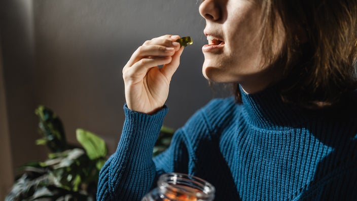 A cropped shot of someone taking a THC gummy.