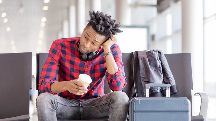 Young man sitting at the airport waiting with a cup of coffee.