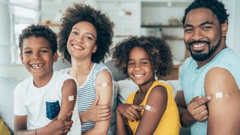Health: Covid 19: family of four showing COVID shot bandaid-1328730704