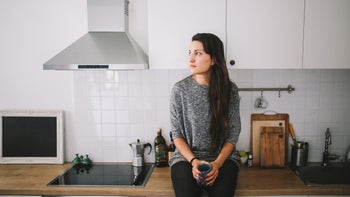 Mental-health: woman sitting alone in the kitchen 1083865112