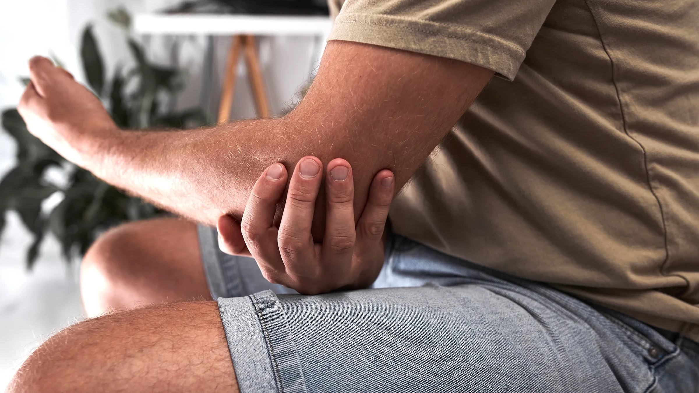 A person is holding their elbow like they are in pain in a close-up.