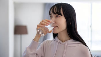 linzess: woman taking medication with water 1898508543