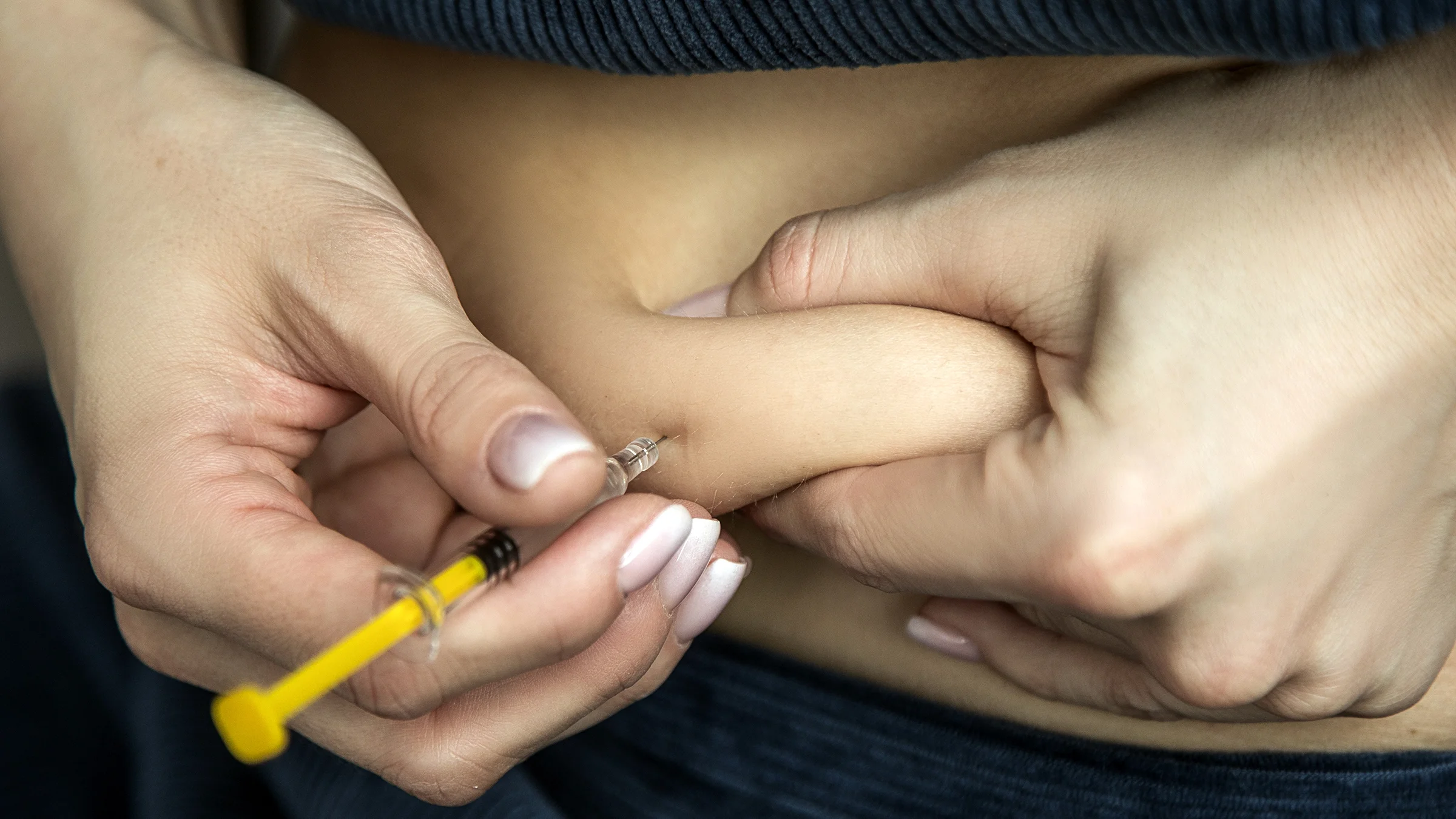 A person injects Lovenox into their stomach.
