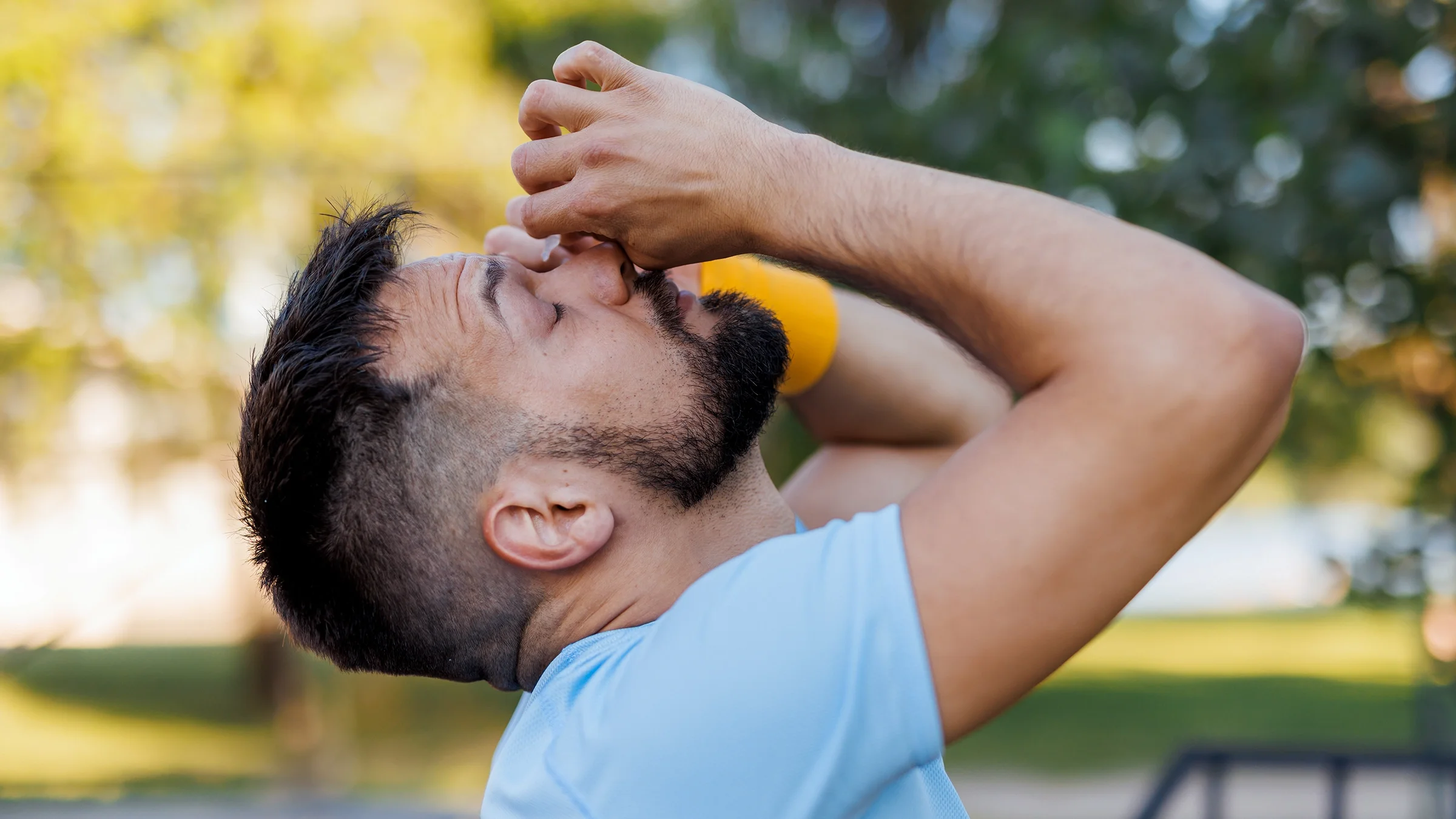 A man is applying eye drops in one eye.