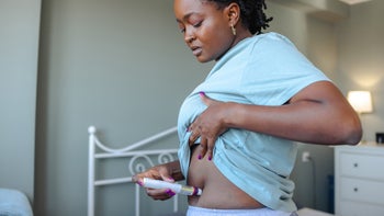 GLP-1 agonists: woman administering stomach injection 2191410978