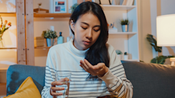 A person holding a glass of water in one hand and a pill in the other.
Tirachard/iStock via Getty Images Plus